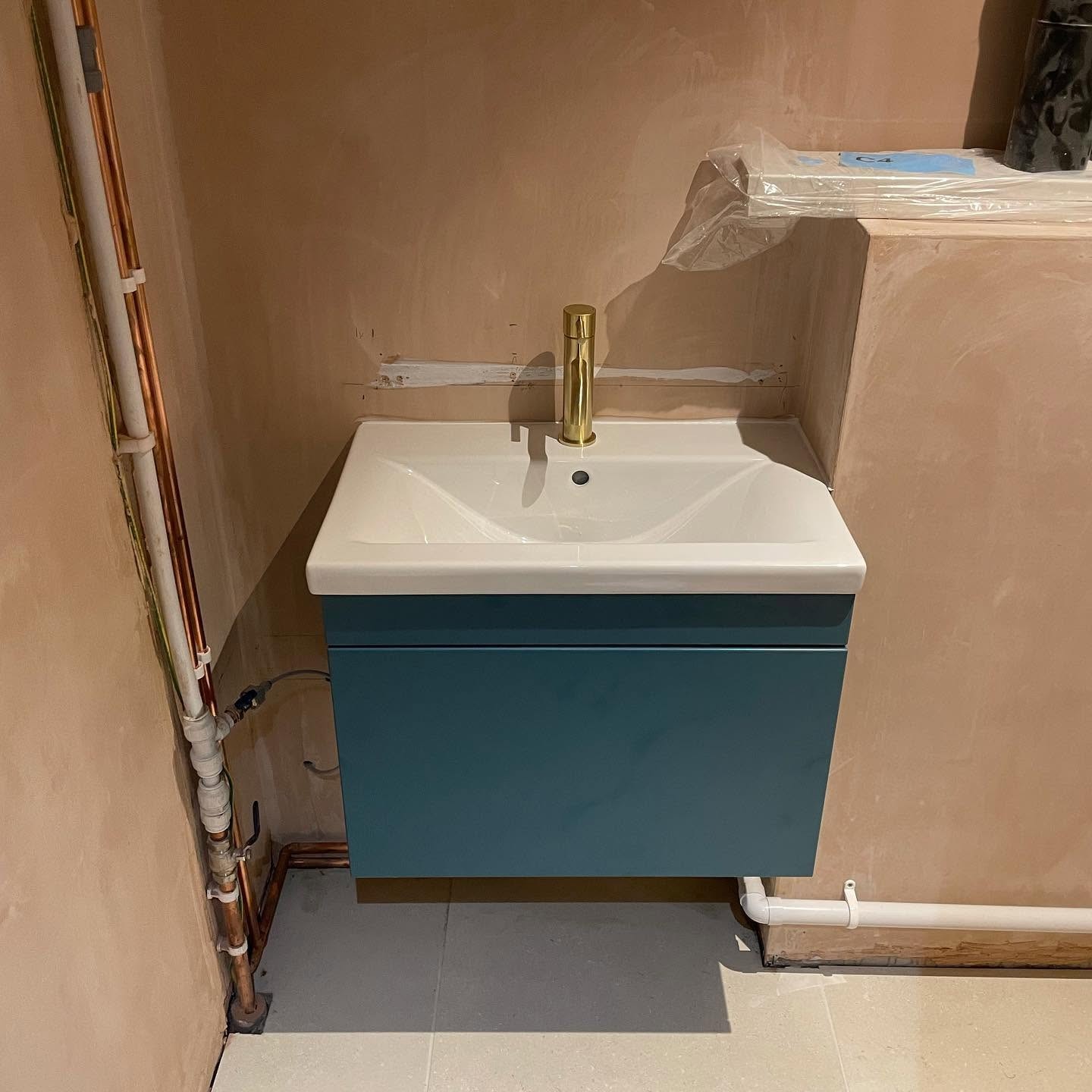 Blue vanity unit with brass tap installed during a cloakroom plumbing installation