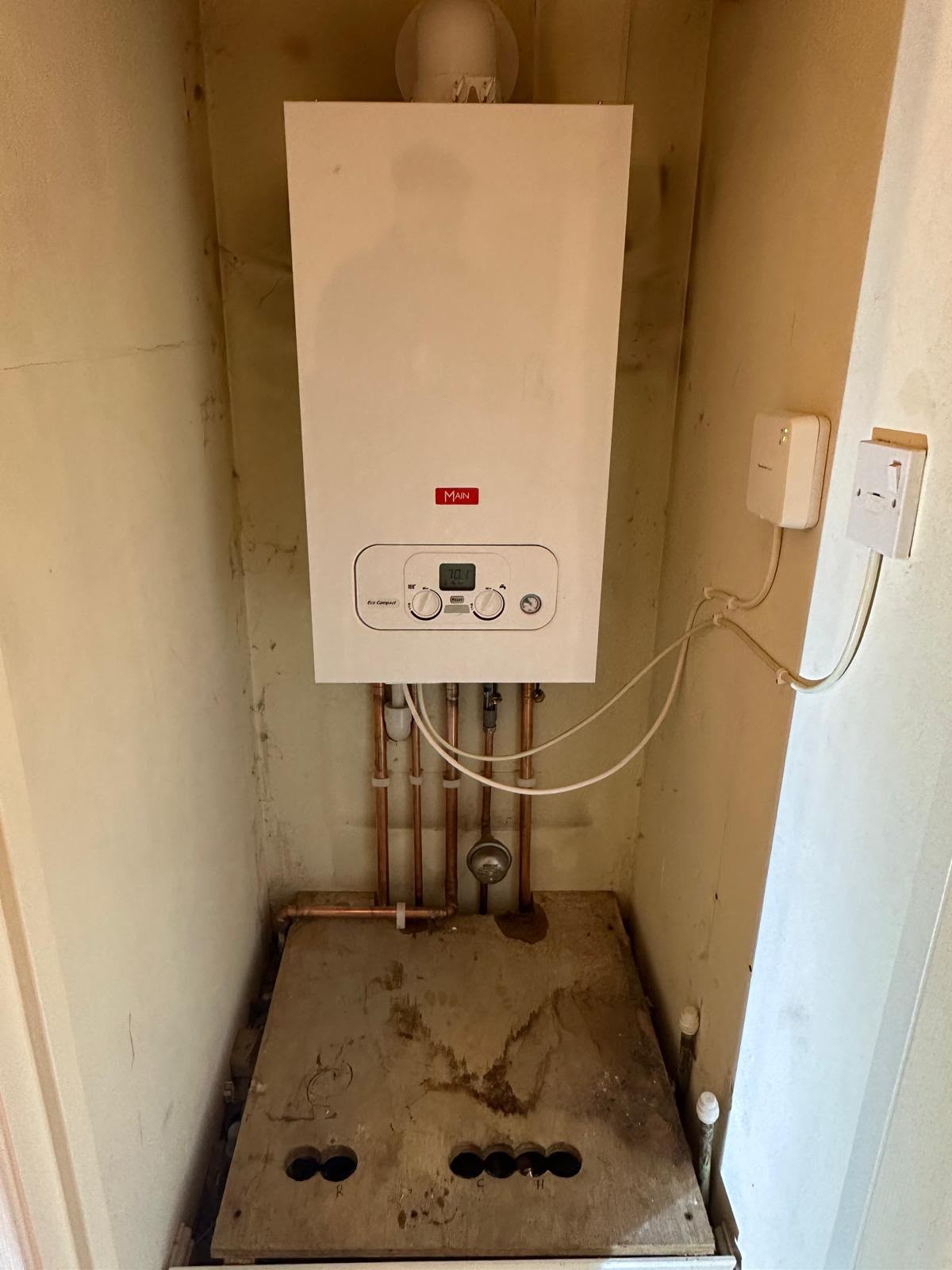 Main branded combi boiler installed in a cupboard with copper pipework below